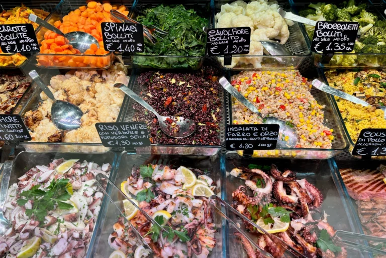 A busy counter of prepared dishes, salads and vegetables.