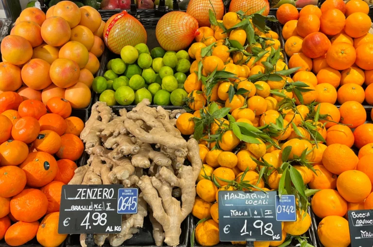 Oranges, lemons and ginger piled high on a colourful produce display.